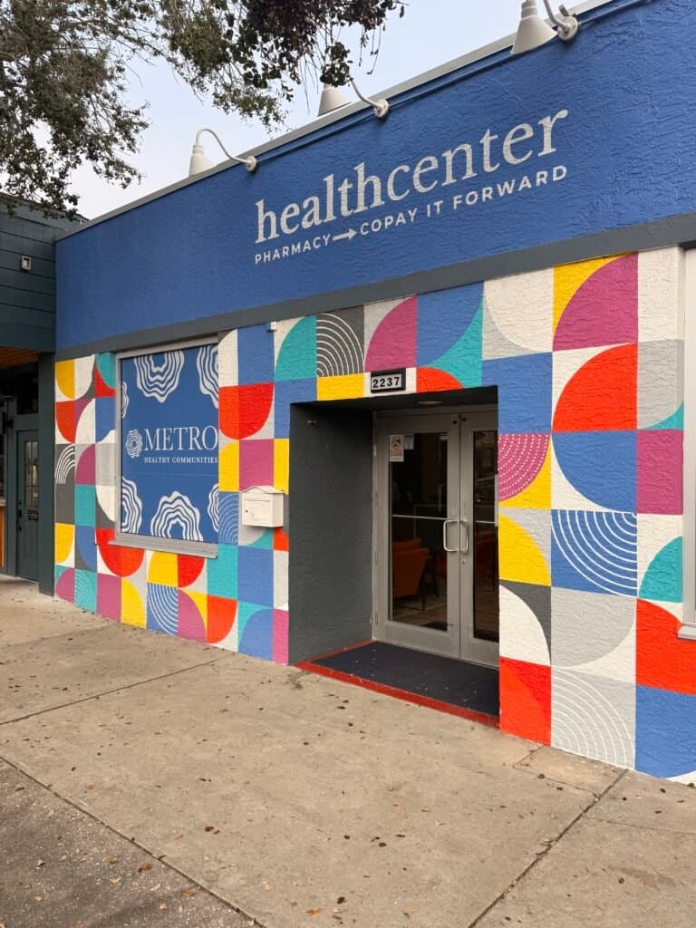 Exterior of the Metro Healthy Communities health center and pharmacy, featuring a brightly colored geometric mural on th